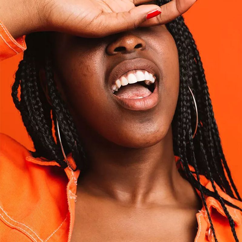Kvinde iført orange bag orange baggrund med hånd, der dækker øjne og åben mund