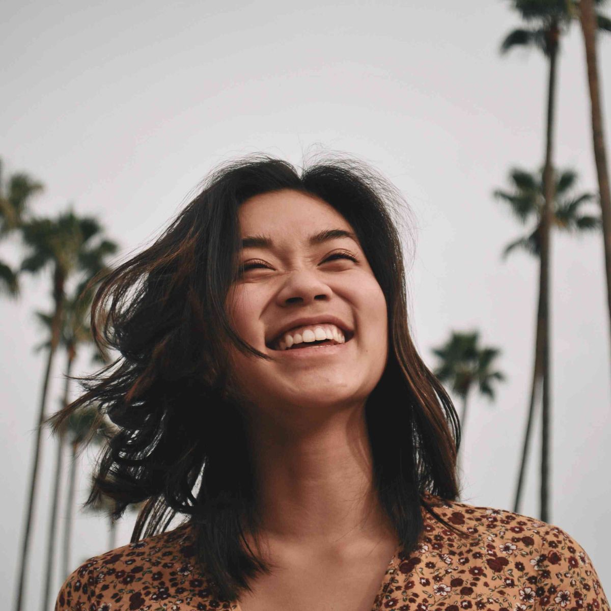 ženska, ki se smeji pod palmami