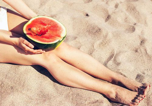 Frau mit nackten Beinen hält eine Wassermelone