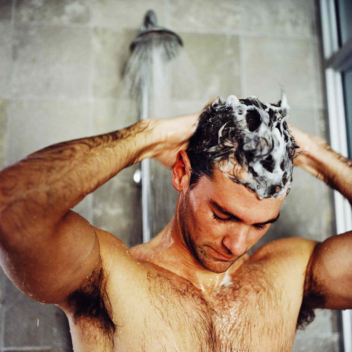 mies pesee hiuksensa suihkussa