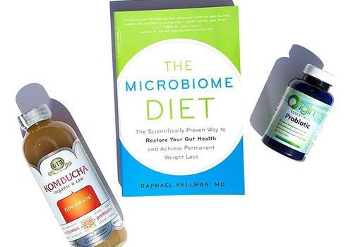 Sticla de Kombucha, cartea Dieta Microbiomului și o sticlă de suplimente probiotice pe fundal alb
