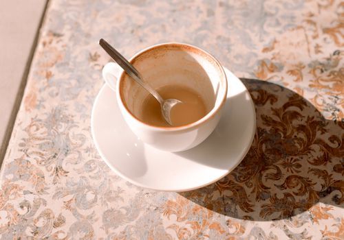 eine fast leere Tasse Kaffee auf einer Fliesentheke mit einem kleinen Löffel in der Tasse