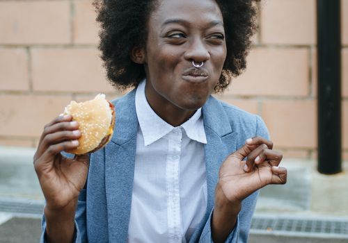 Juodoji moteris valgo greito maisto sumuštinį