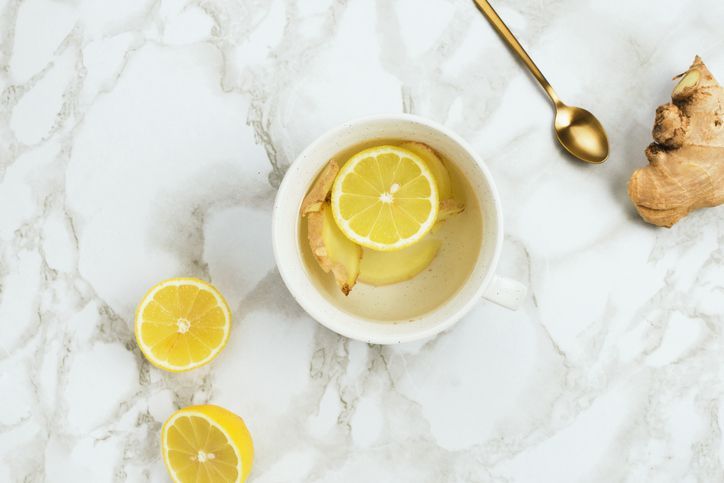 Flatlay des gesunden Getränks mit Zitrone und frischer Ingwerwurzel auf Marmorhintergrund