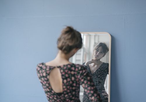 Mujer joven, llevando, un, vestido floral, mirar en un espejo
