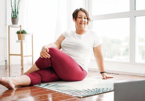 Kvinde, der praktiserer yoga i stuen
