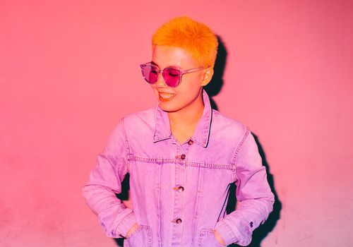 androgyne asiatische Person, die in rosa lächelt
