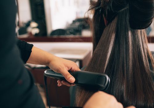 Brunt hår bliver fladt stryget i en salon