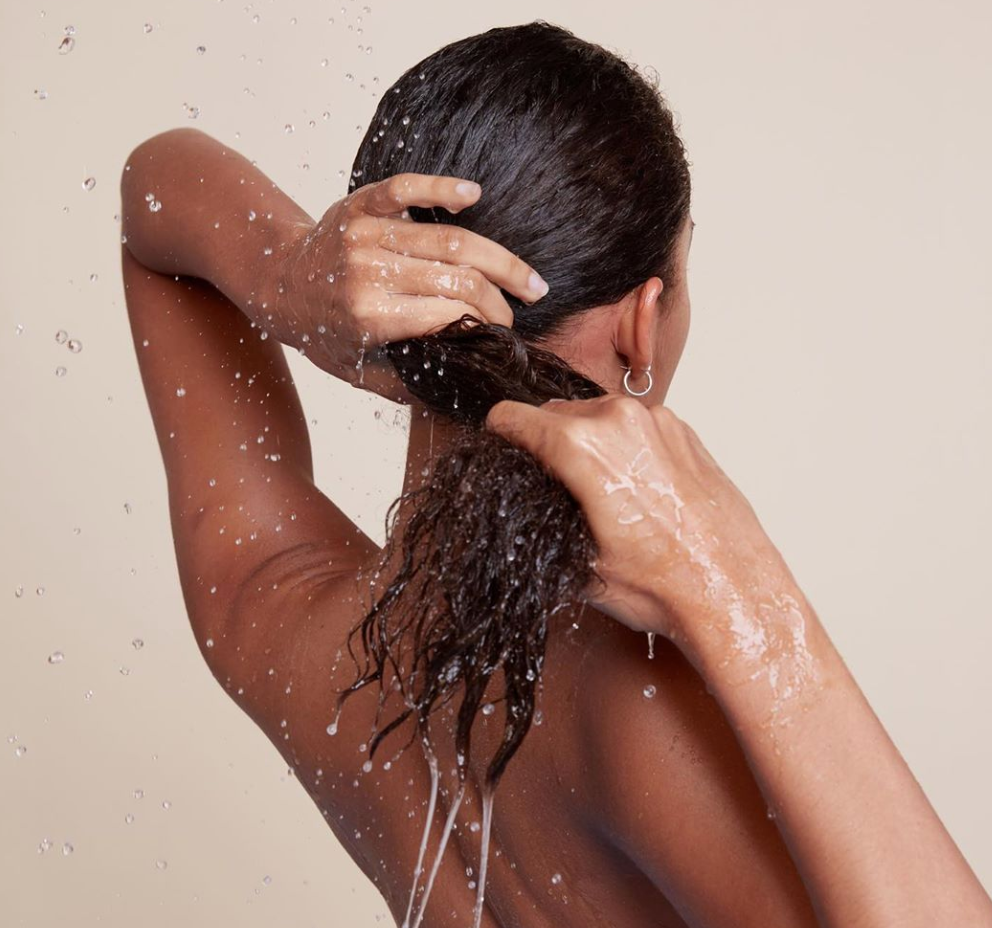 vrider håret ud under brusebadet