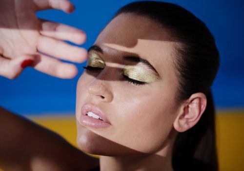 Brunetka, ženský model so zatvorenými očami a zlatým očným tieňom
