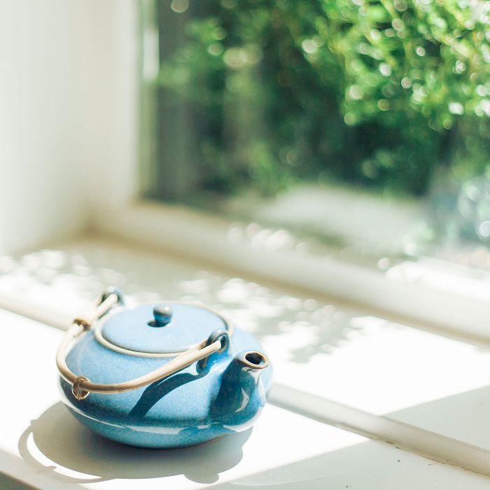 Bule de chá azul no peitoril da janela