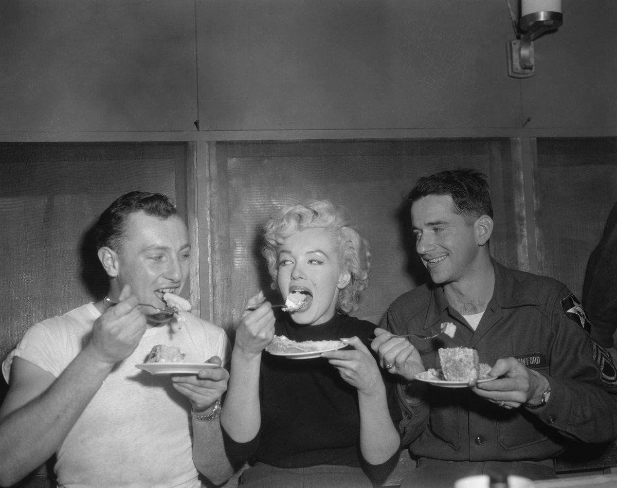 Marilyn Monroe isst zwischen zwei Soldaten