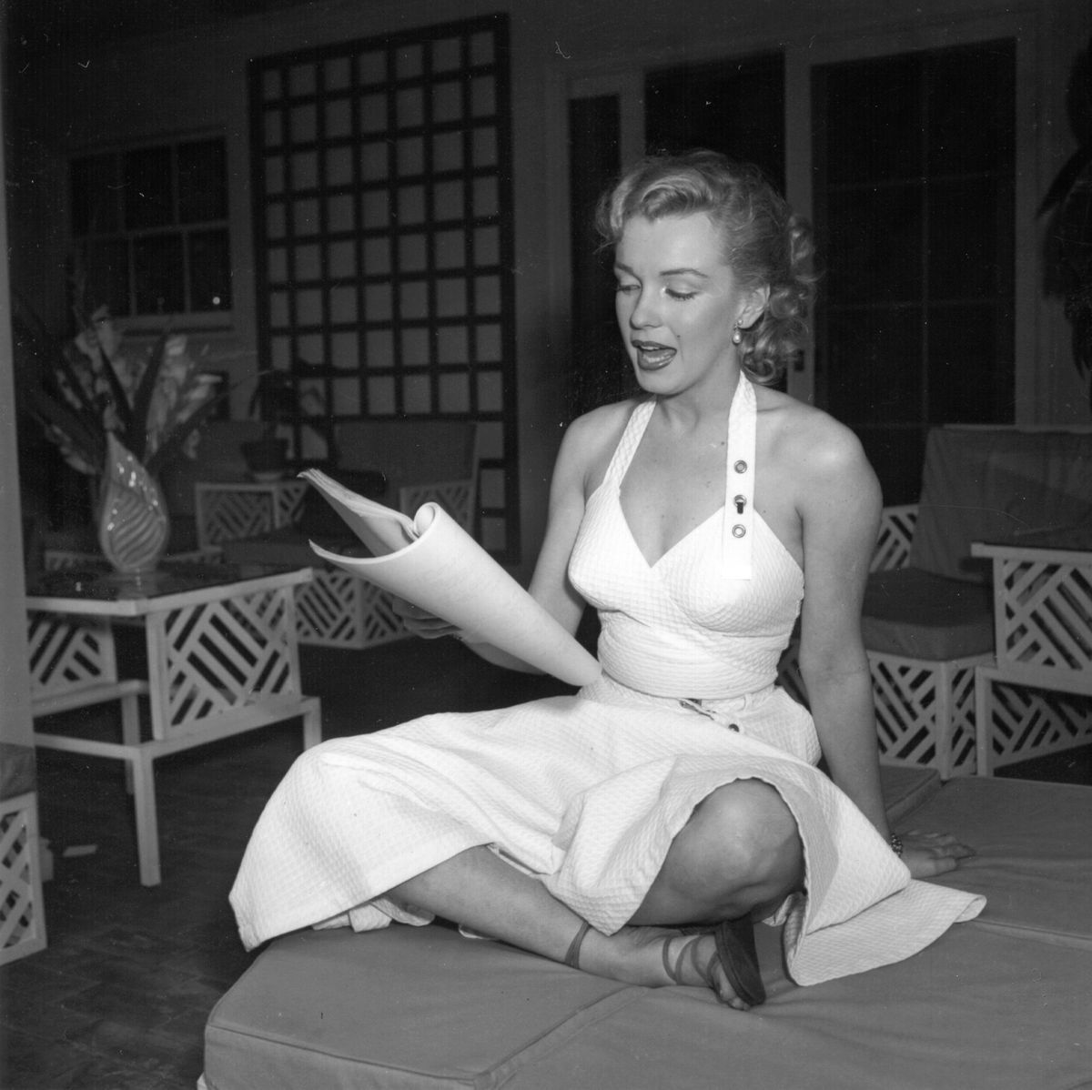Marilyn Monroe sitzt mit gekreuzten Beinen und liest ein Buch