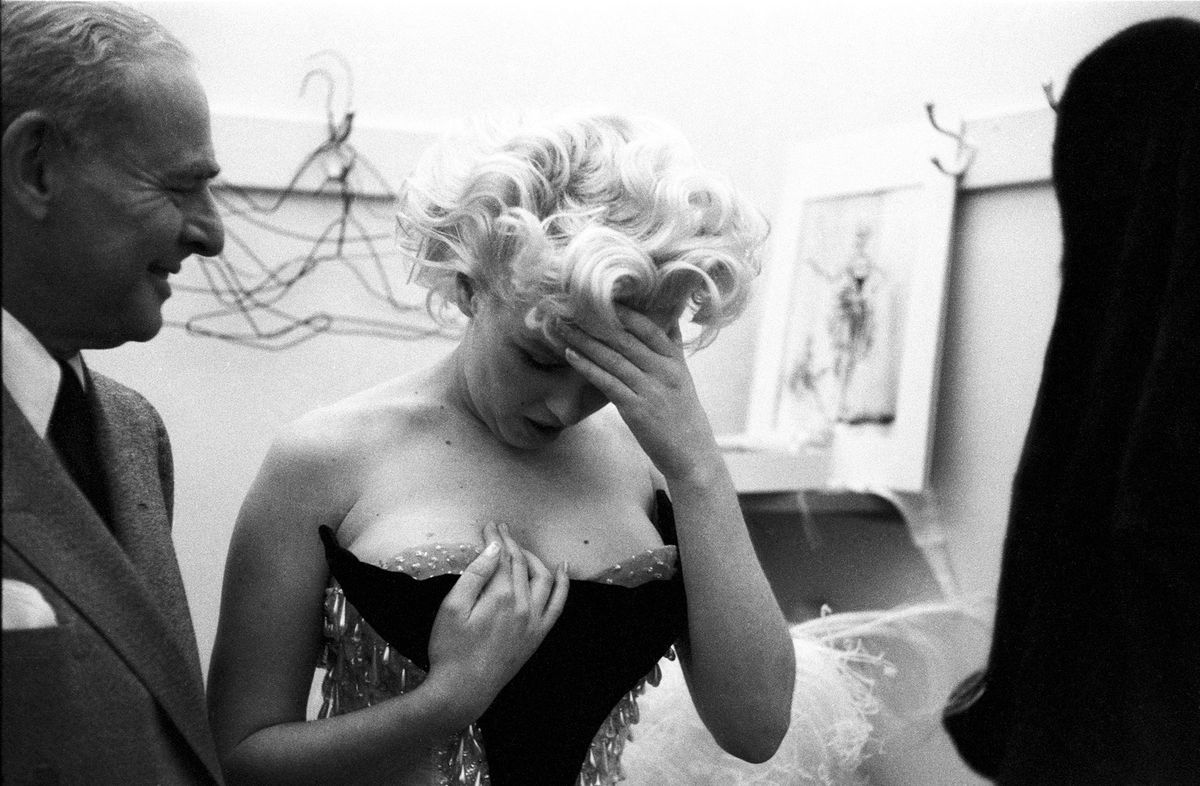 Marilyn Monroe schaut mit dem Kopf auf der Vorhand auf ihr Kleid herab