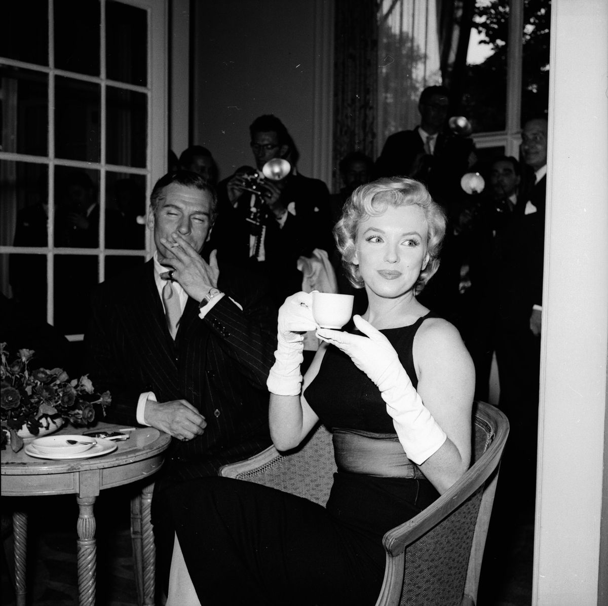 Marilyn Monroe trinkt Tee und trägt lange Handschuhe auf einer Party