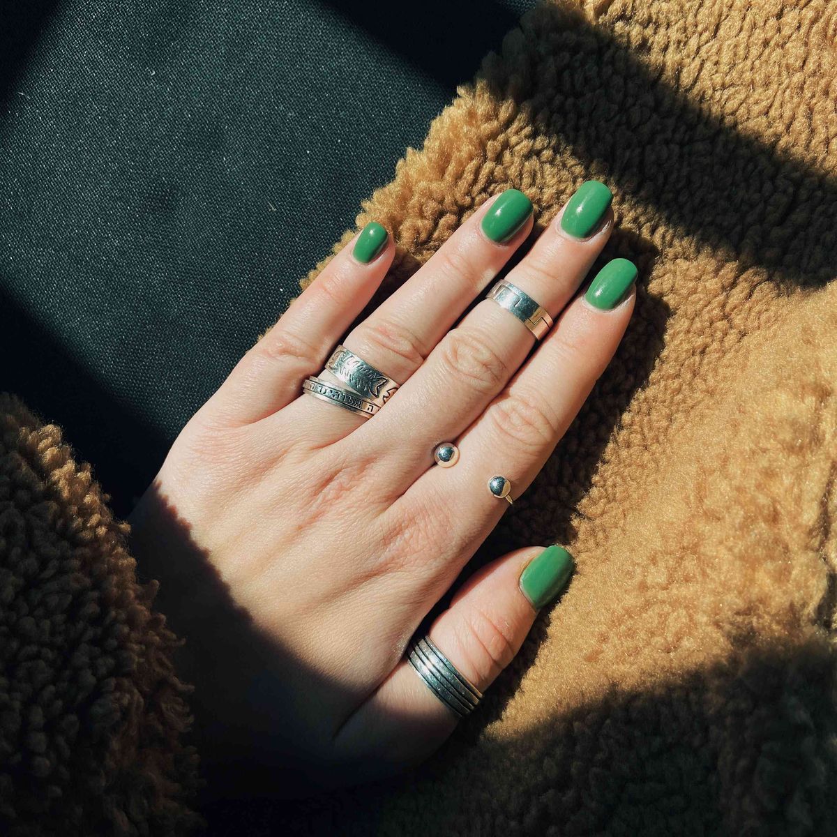 grøn manicure mod furry stof med sølvringe