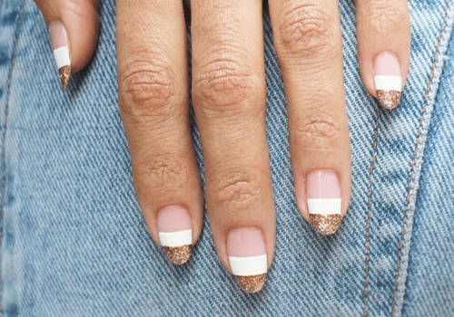 Diseño de uñas de rayas blancas y doradas sobre fondo de mezclilla