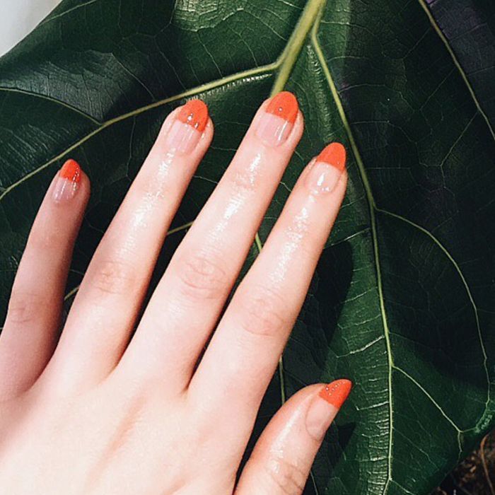 葉に対してオレンジ色のマニキュアと手