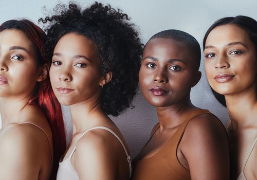 Fire unge kvinder med forskellige hårtyper mod en grå baggrund