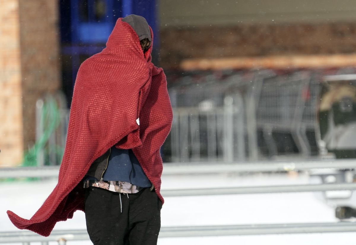 Ein Mann läuft mit einem Sweatshirt und einer Decke herum, um warm zu bleiben