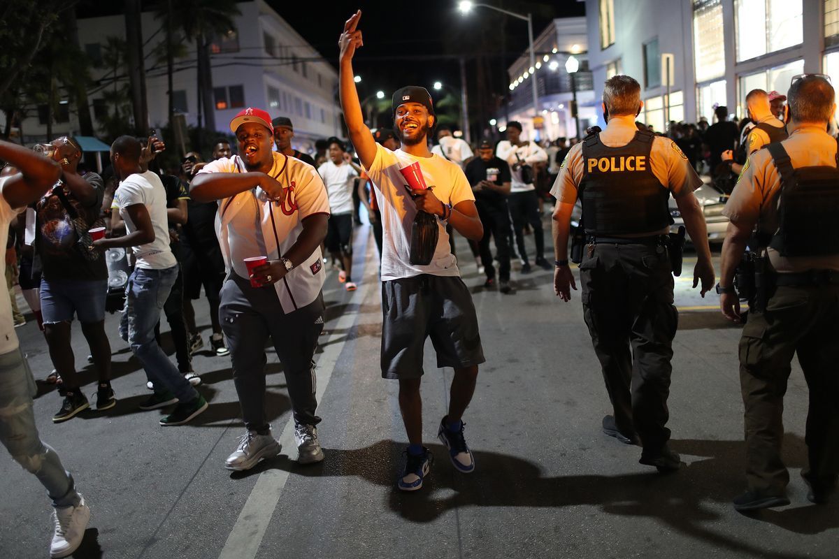 한 무리의 경찰이 지나갈 때 빨간색 솔로 컵을 들고 손을 흔드는 남자 그룹