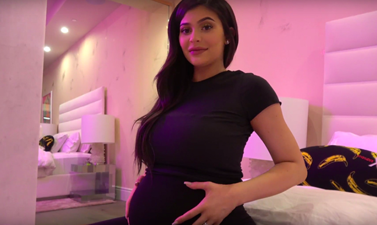 Kylie steht mit den Händen auf ihrem schwangeren Bauch