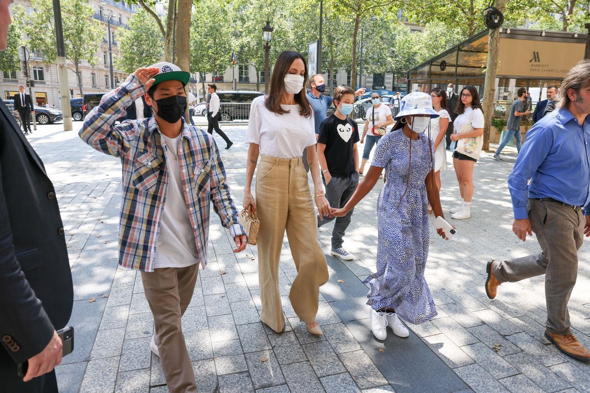 Angelina trägt eine Maske und hält Händchen mit zwei ihrer Kinder, ebenfalls maskiert