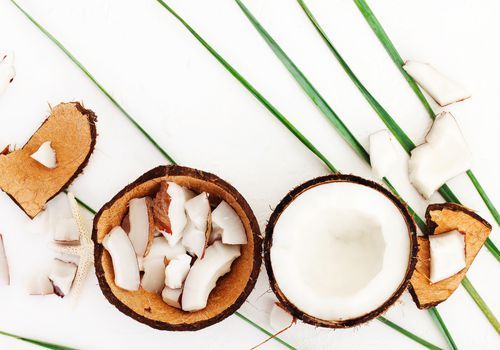 Stykker kokosnød og kokosnødskal på hvid baggrund