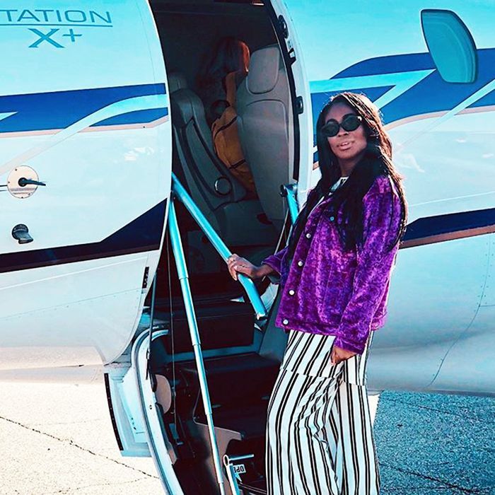Frau mit lila Mantel an Bord eines Flugzeugs
