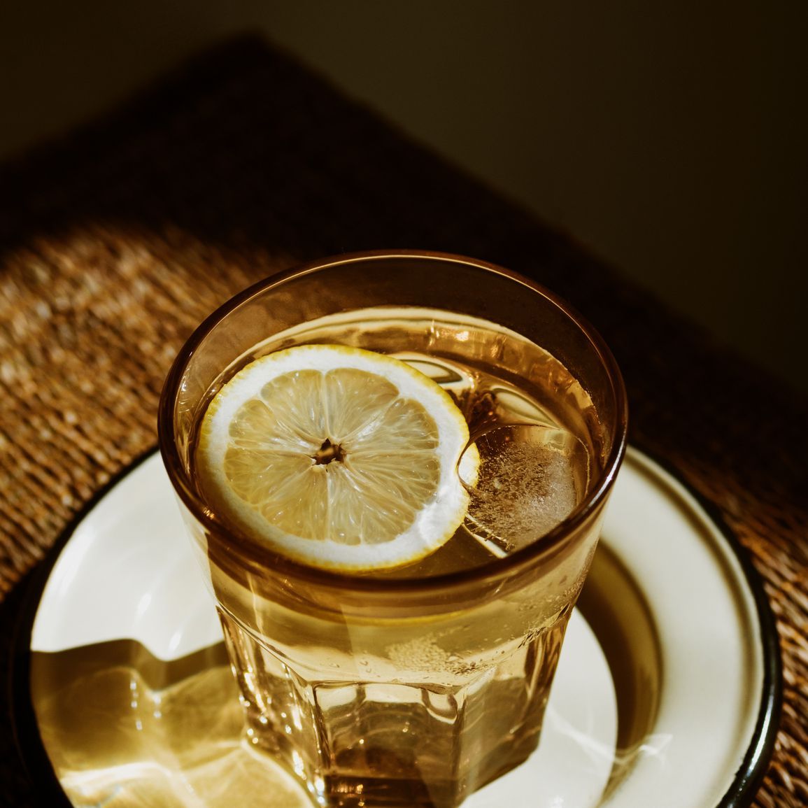 Чаша воде са лимуном на тањиру