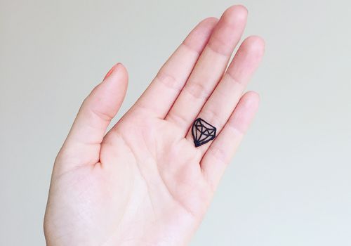 Hand mit Diamant Tattoo auf Ringfinger
