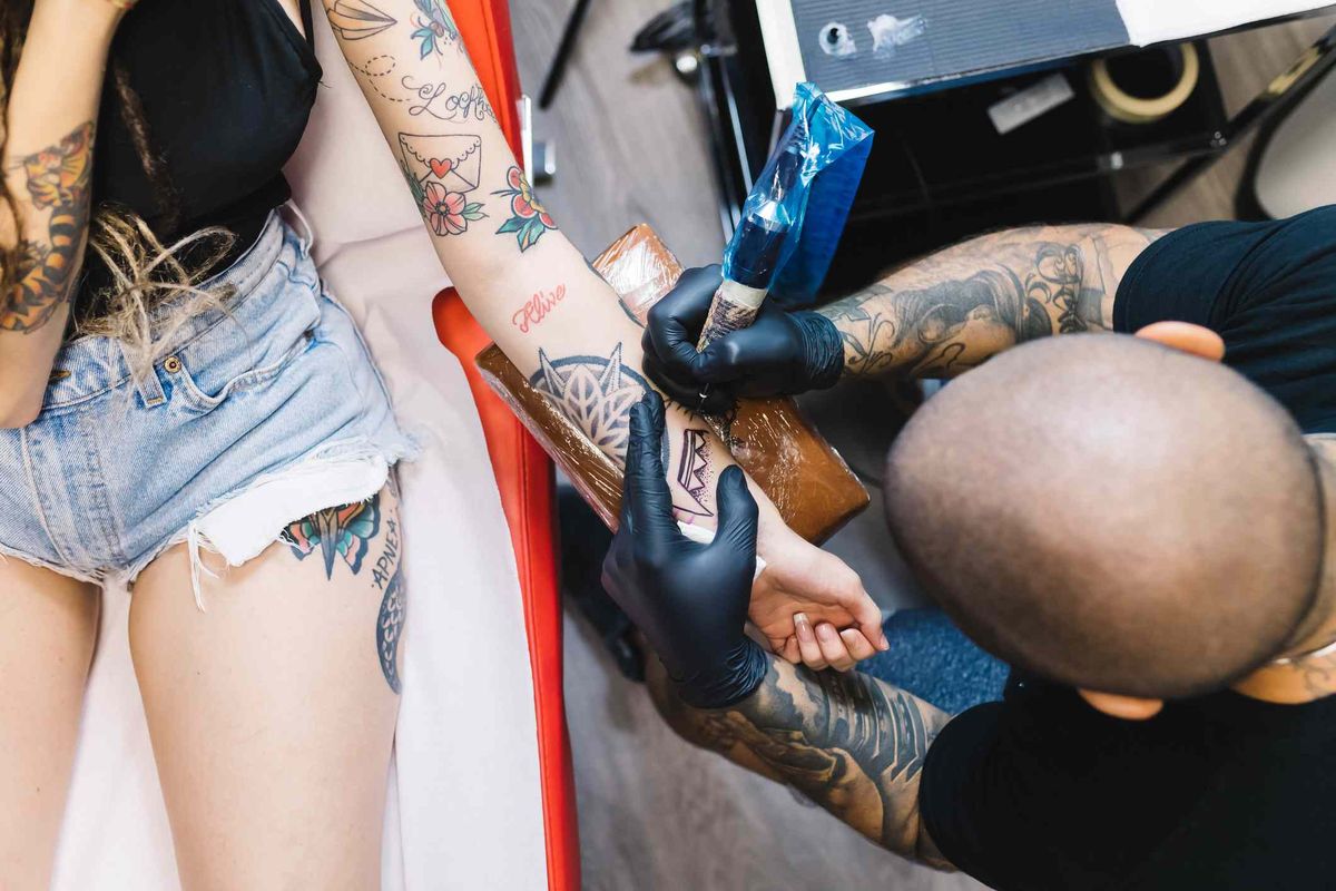 Tatuiruočių meistras klientui tatuiruoja ranką