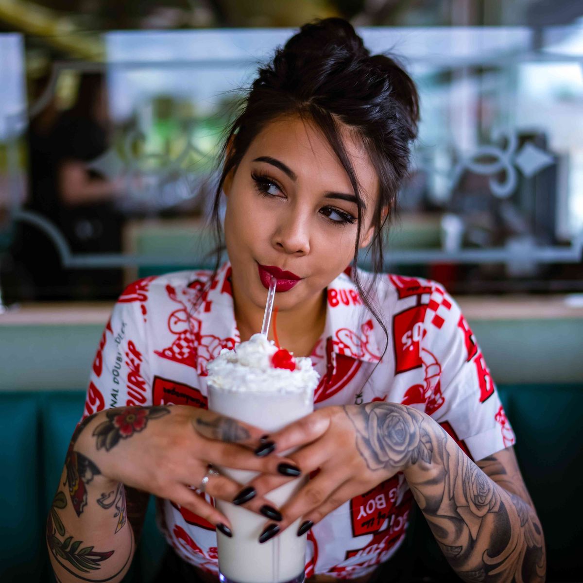 kvinde med tatoveringer, der drikker en milkshake