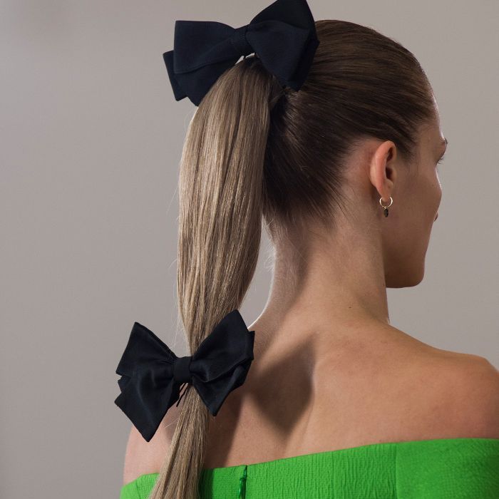 דוגמנית לובשת את שערה בקוקו מאובטח בשתי קשתות שחורות